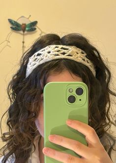 a woman taking a selfie with her cell phone in front of her face while wearing a tiara