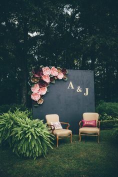 two chairs sitting next to each other in front of a wall with flowers on it