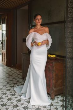 a woman in a white dress holding an orange