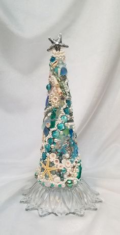 a glass christmas tree with seashells and starfish on it's top