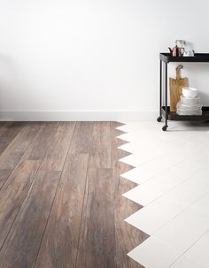 an empty room with white walls and wood flooring on the side, near a black table