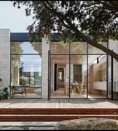 a house with glass walls and wooden decking