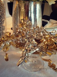 a silver vase filled with flowers on top of a white table covered in confetti