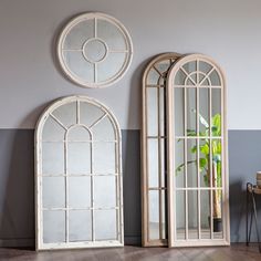 two white arched mirrors sitting next to each other on top of a hard wood floor