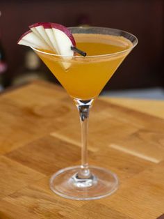 an apple sits on top of a drink in a martini glass, ready to be served