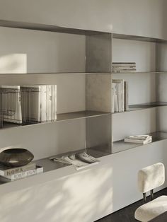 a white shelf with books and magazines on it in a room that is mostly empty