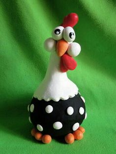 a ceramic chicken sitting on top of a black and white polka dot covered egg with an orange beak