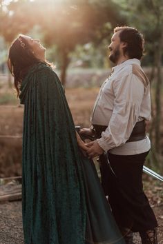 a man and woman dressed in medieval clothing standing next to each other with their eyes closed