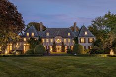 a large house with lots of windows and lights on it's front lawn at night