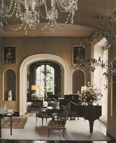 a living room filled with furniture and a chandelier hanging from the ceiling over a piano