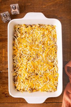 a casserole dish filled with cheese and other toppings on a wooden table