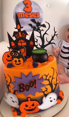 a baby sitting in front of a halloween cake