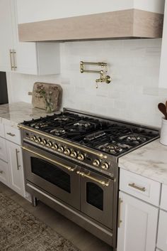 a stove top oven sitting inside of a kitchen next to white cabinets and counter tops