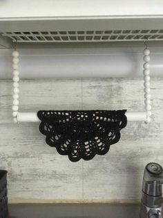 a black doily hanging from the side of a shelf above a stove top oven