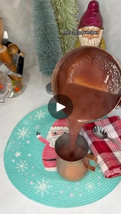 a person pouring something into a pot on top of a blue mat next to a christmas tree