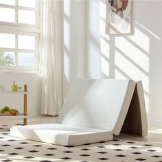 a bed sitting on top of a white floor next to a window