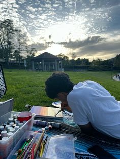 a young man is painting in the grass