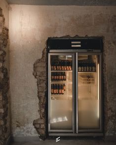 an open refrigerator with drinks in it next to a brick wall