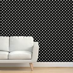 a white couch sitting in front of a wall with black and white designs on it