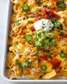 a casserole dish with nachos, cheese and green peppers on top