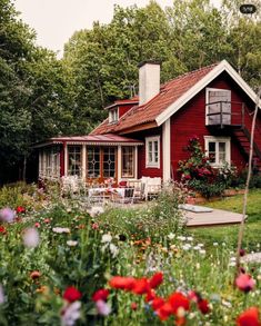 a red house surrounded by flowers and trees