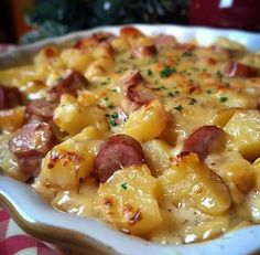 a casserole dish with potatoes and sausages in a white bowl on a table