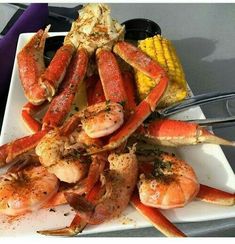 a white plate topped with lobsters and corn