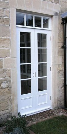 a white double door in front of a brick building with glass panels on the doors