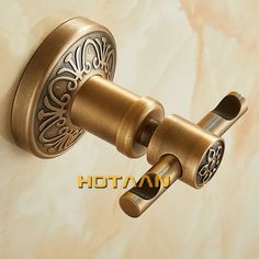 an ornate brass door handle on a white marble background with the word hottamn written below it