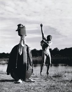 two people standing next to each other in front of a body of water wearing hats and ties