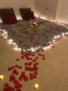 a bed with red petals on the floor and candles in the room next to it