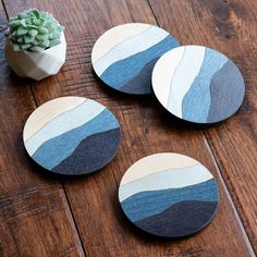 four wooden coasters sitting on top of a wooden table next to a potted plant