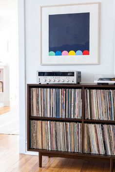 a record player sitting on top of a wooden cabinet next to a wall mounted art