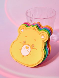 there is a cup with a bear on it next to some coasters that are shaped like rainbows