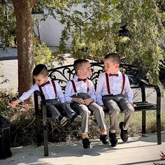 three young boys sitting on a park bench