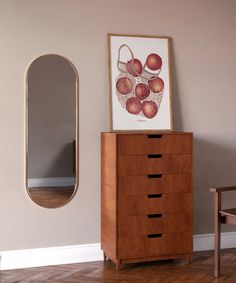 a dresser and mirror in a room with wood flooring next to a painting on the wall