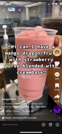 a pink drink in a plastic cup sitting on top of a counter