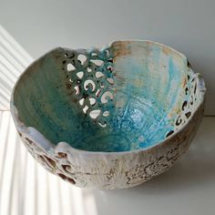 a blue and white bowl sitting on top of a counter next to a wall with light coming through it