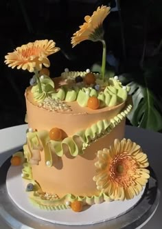 a three tiered cake with yellow flowers on the top and bottom, sitting on a plate