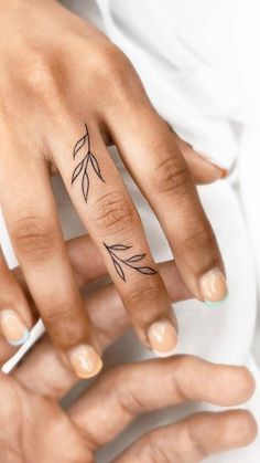 a woman's hand with a small tattoo on the middle finger and an arrow