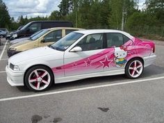 a white car with hello kitty painted on it's side in a parking lot