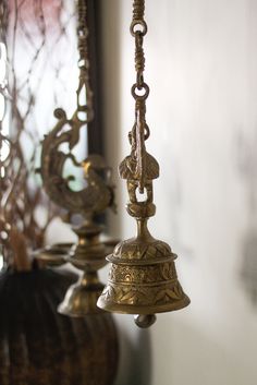 two brass bells hanging from the ceiling in front of a mirror