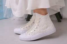 a woman's white high top sneakers with lace and pearls on the bottom, as seen from behind