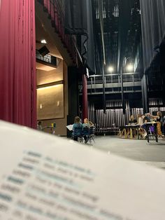 an open book sitting on top of a table in front of a red stage curtain