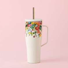 a white coffee cup with colorful flowers painted on the side and a straw sticking out of it