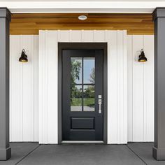 a black front door with two lamps on each side and white walls behind the doors