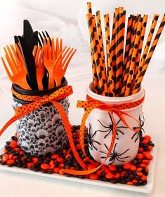 two jars filled with orange and black paper straws on top of a white plate