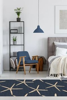 a bed room with a neatly made bed next to a blue chair and a book shelf