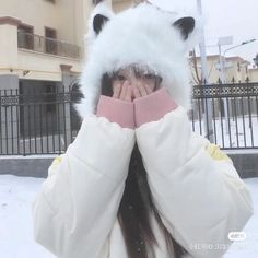 a girl covers her face with a furry hat