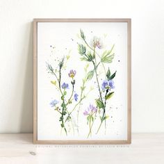 a watercolor painting of wildflowers on a white background in a wooden frame